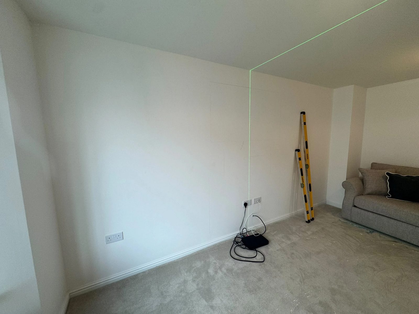Stage 1 — bare living room wall marked out with a laser level